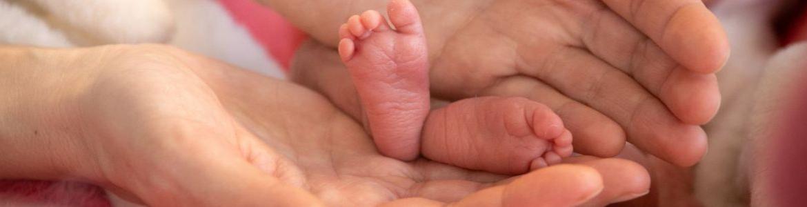Piececitos de un bebé prematuro entre las manos de un adulto