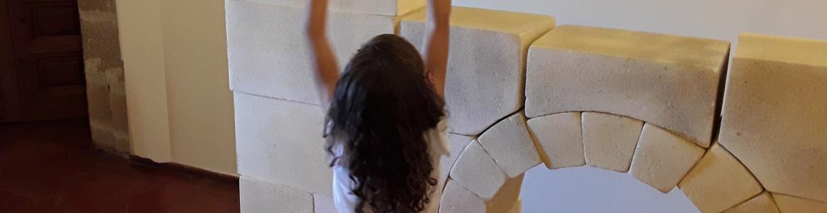 Niña jugando con bloques creando un arco y una torre arquitectónica