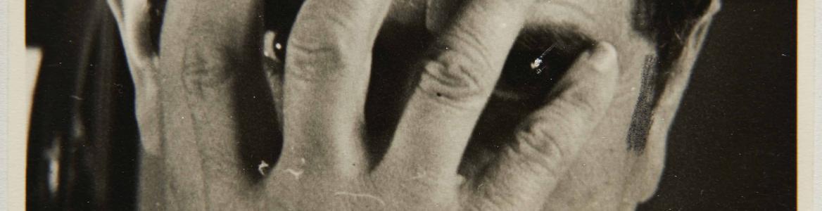 Fotografía en blanco y negro de un hombre ocultándo su rostro con una mano