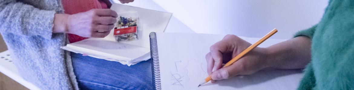 Dos chicas sentadas, enfrentadas, apuntando notas en sendos cuadernos