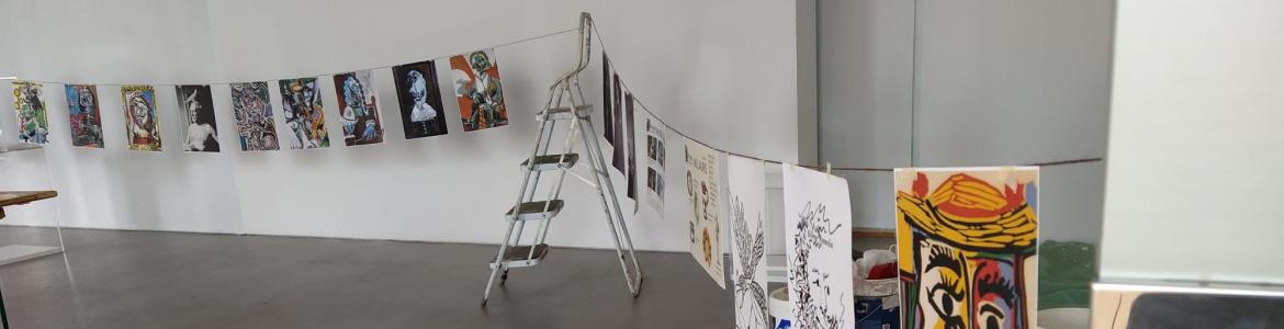 Varios dibujos y pinturas colgados de una cuerda sujeta en una escalera