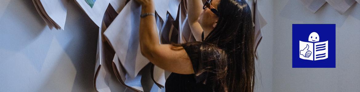 Mujer joven con gafas cogiendo un folleto en papel de la pared