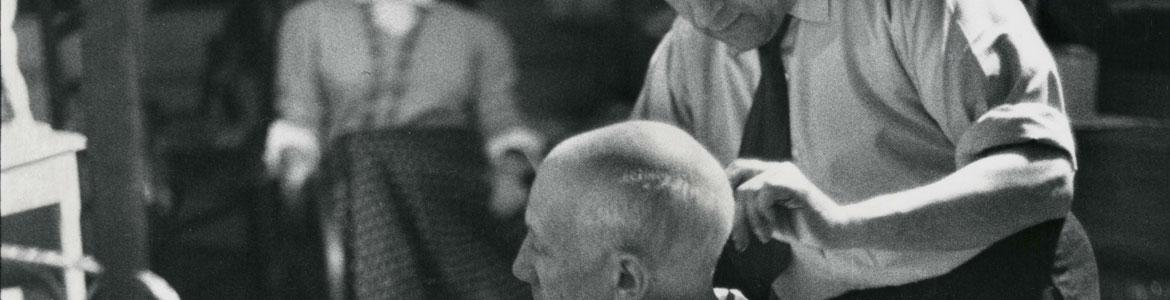 Fotografía en blanco y negro de David D. Duncan en la que aparece Picasso sentado mientras su barbero Eugenio Arias le corta el pelo