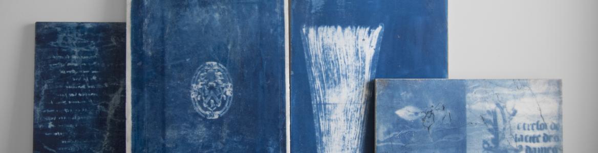 Blue canvases with abstract drawings resting on the floor