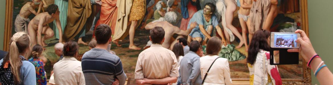 Grupo de personas observando un gran cuadro histórico con escena bíblica 