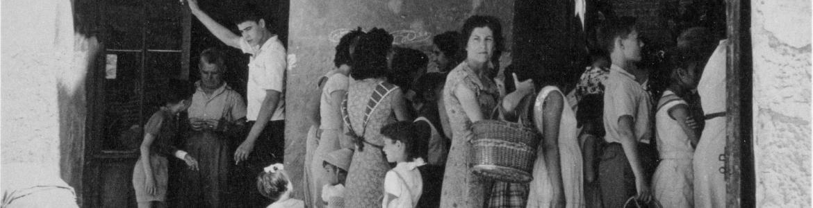 Foto en blanco y negro con gente haciendo cola en la puerta de una peluquería antigua