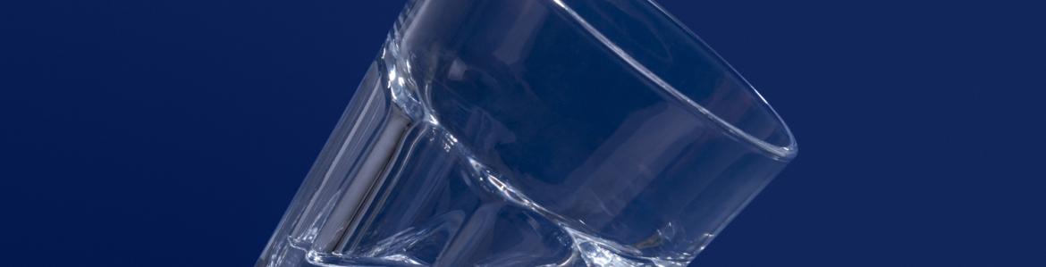 Vaso lleno a medias de agua sobre fondo azul