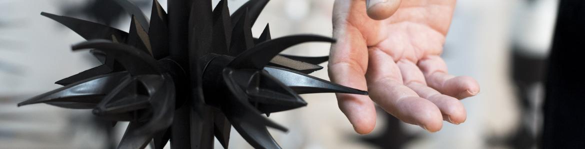 Thistle-shaped iron sculpture and, with its skewers, seems to prick a hand