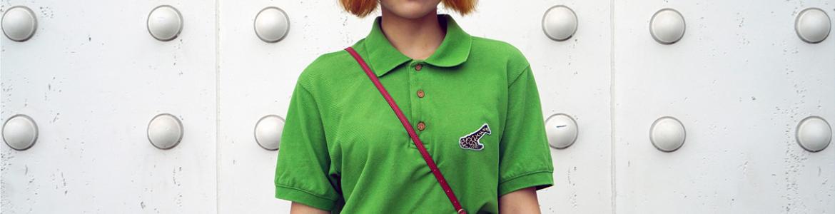 Chica con pelo teñido de rubio, gafas de sol amarillas y polo verde
