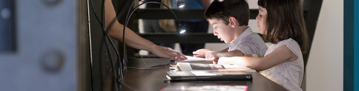 Two children looking at a book in a showcase in an exhibition hall