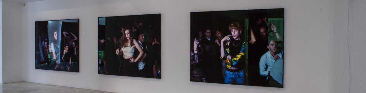 Three large format photographs hanging on a white wall