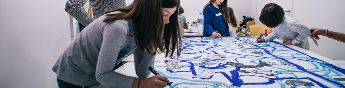 Niños pintando con pinceles líneas curvas en distintos tonos de azul