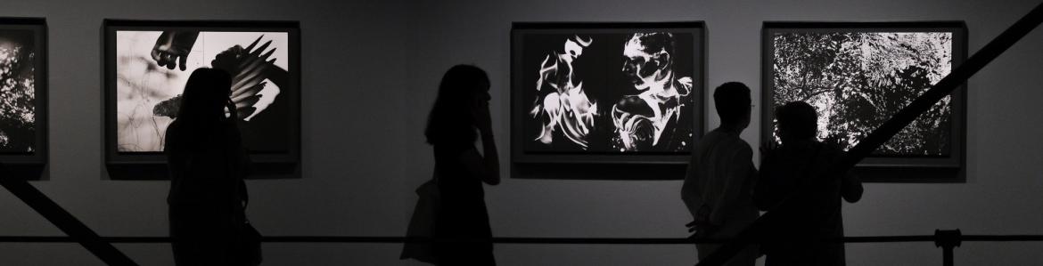 Cuatro personas viendo las fotografías en blanco y negro de David Jiménez en la sala de exposiciones de Canal