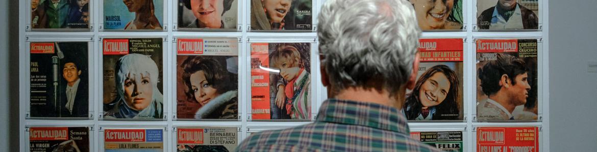 Hombre mirando portada de revistas expuestas en una pared