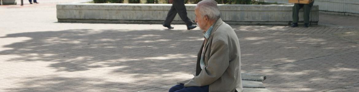 hombre mayor sentado en un banco de la calle