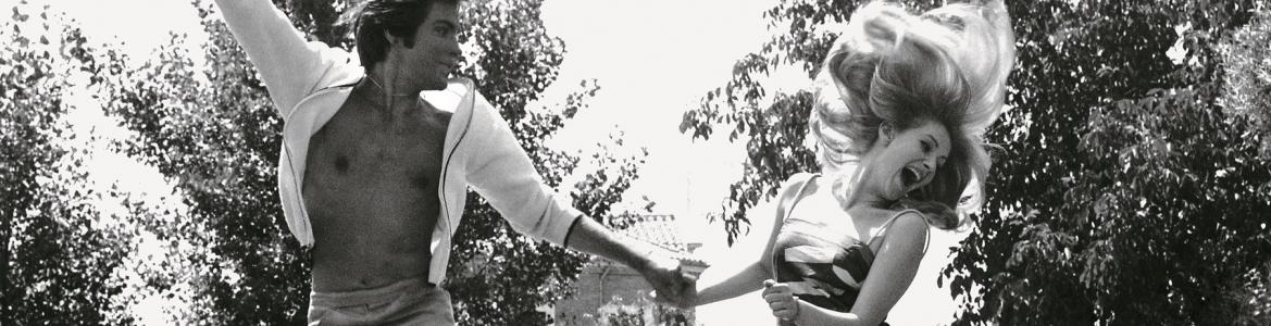 Image of a couple in a garden jumping in the air while holding hands