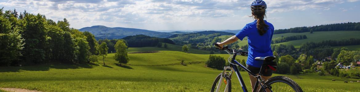 Ciclista de espaldas contemplando un paisaje verde