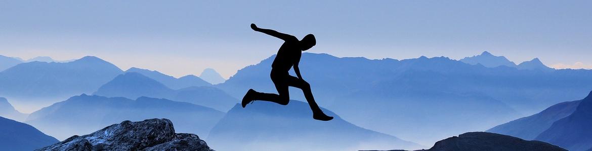 Image of male silhouette jumping from one mountain to another