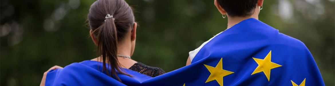 Dos jóvenes con una bandera de la UE en sus espaldas