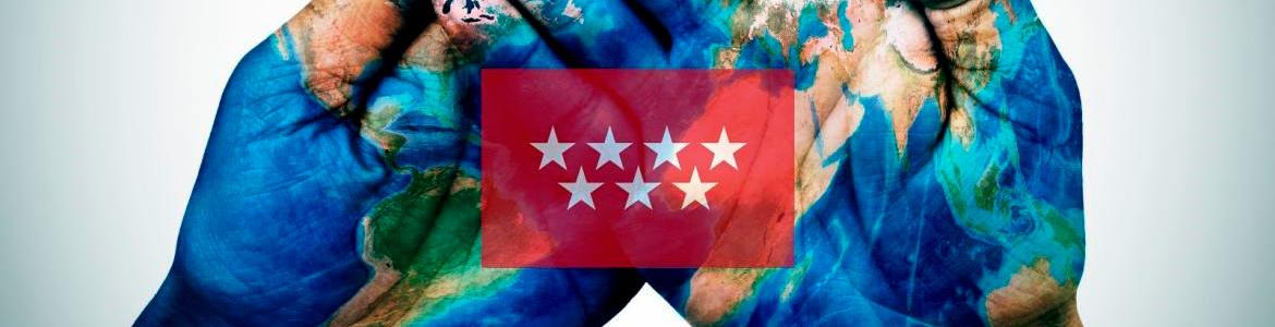 Manos cruzadas con el mapamundi y la bandera de la Comunidad de Madrid