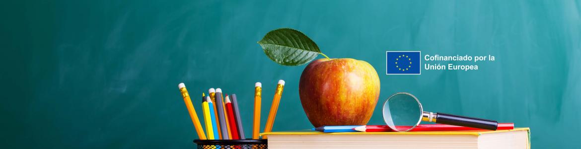 Blackboard, desk, pencil holder with pencils and apple
