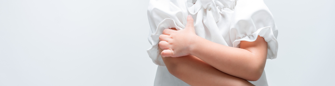 La mano izquierda de una niña pequeña rascando su brazo derecho