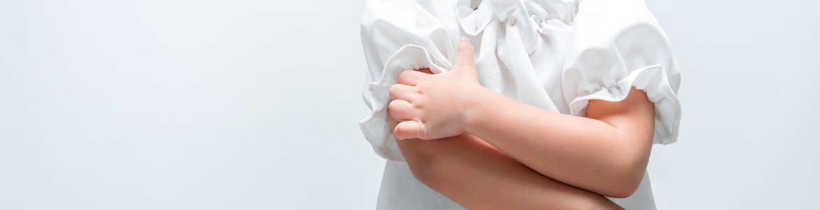 La mano izquierda de una niña pequeña rascando su brazo derecho 