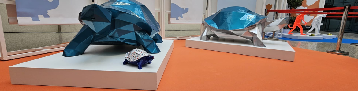 Dos esculturas geométricas azules de tortugas y al fono otra roja de un mono