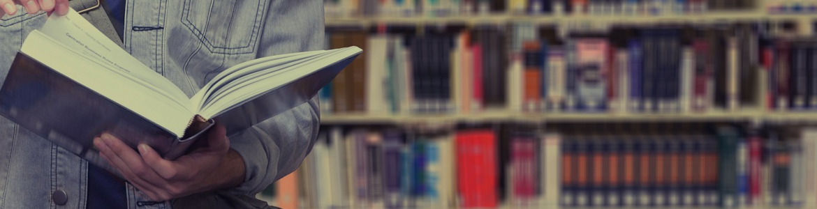 Imagen de persona ojeando un libro en una biblioteca