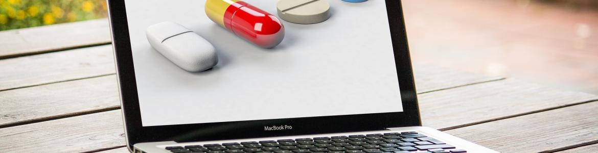 ordenador portátil abierto y con pastillas de medicamentos en la pantalla