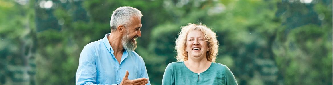 Pareja de mediana edad paseando por el bosque sonrientes