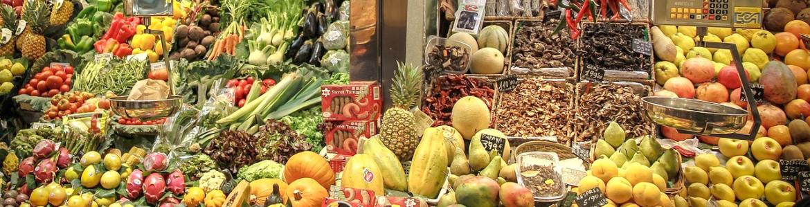 frutas y verduras a granel y envasadas en un expositor en una frutería de un mercado