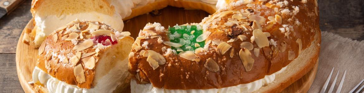 Roscón relleno con nata y un trozo cortado, sobre una mesa de madera