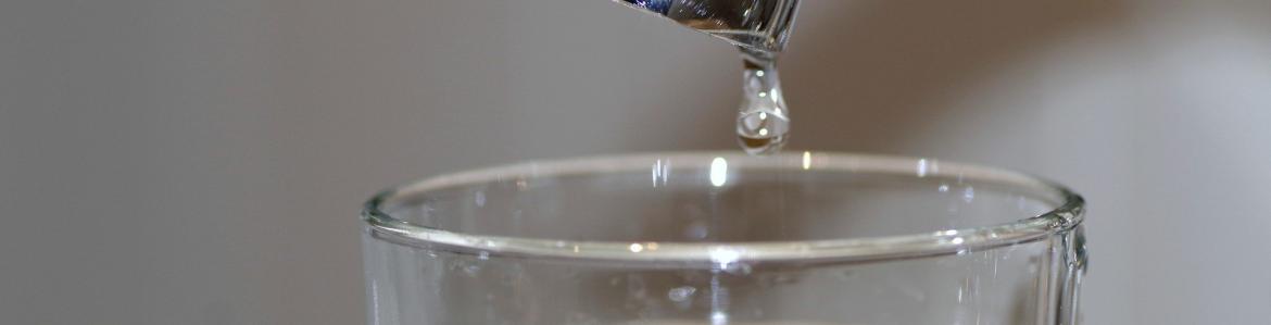 Grifo con una gota sobre un vaso con agua