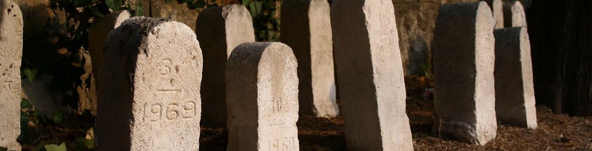 Lápidas sencillas frente a la pared de un cementerio