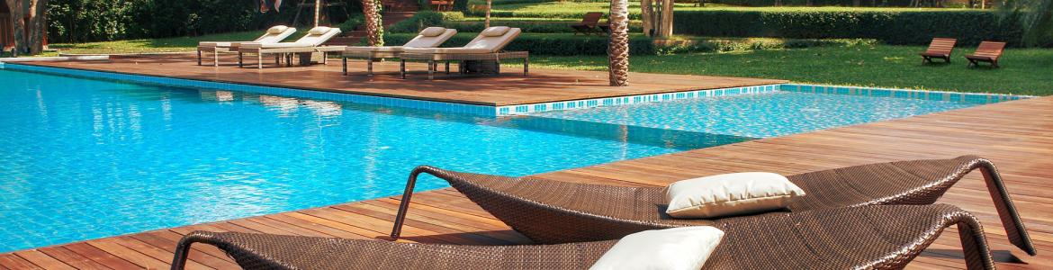 Piscina de una urbanización, con suelo de madera y tumbonas en forma de barca