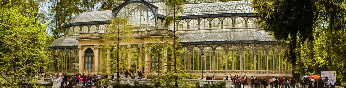 Vista del Palacio de Cristal del Parque del Retiro de Madrid con el estanque en primer plano en primavera