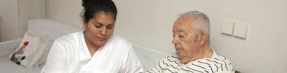Mujer joven sentada junto a hombre mayor mirando un libro