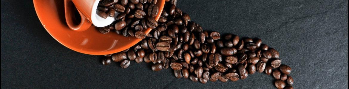 Taza de color terracota volcada con granos de café