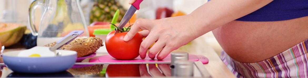 Embarazada cortando un alimento en la cocina