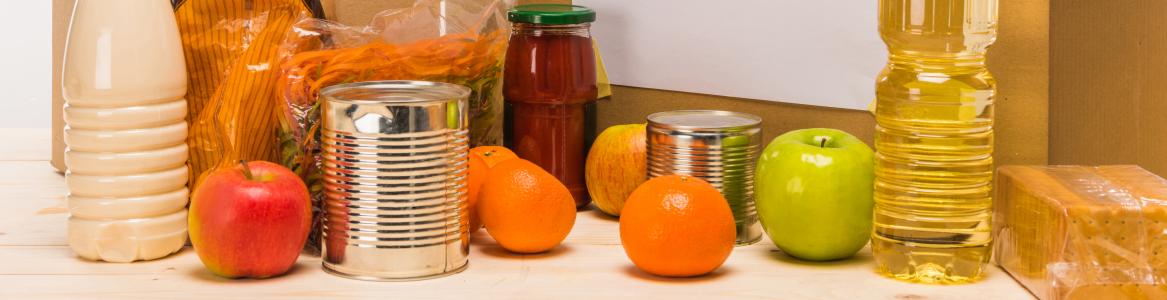 Caja con un cartel donde se lee "donación junto a diferentes alimentos