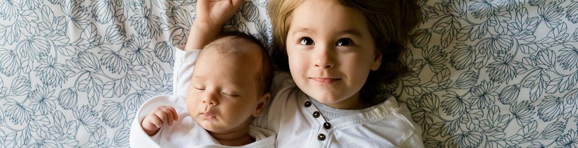 Bebé con su hermana encima de una cama