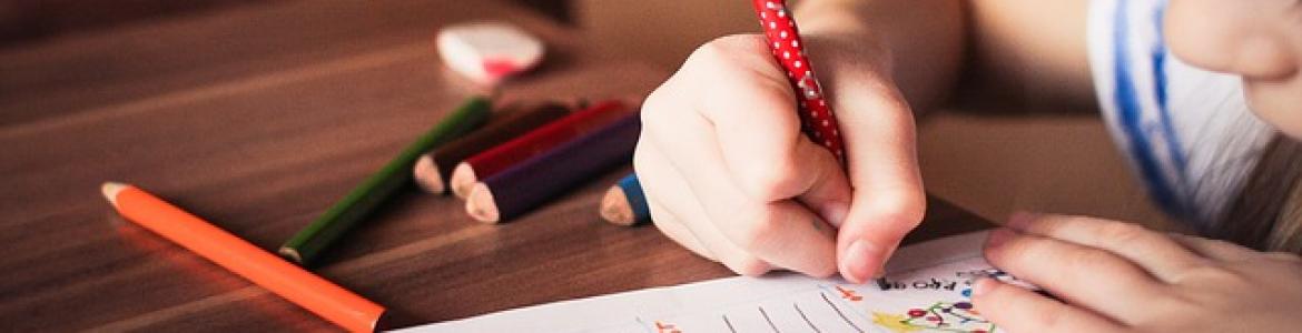 niña escribiendo en una hoja sobre una mesa