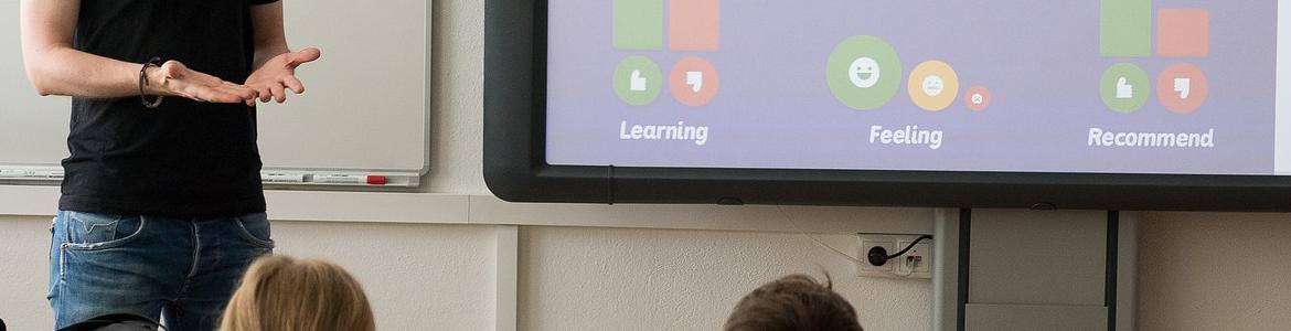 Profesor explica a los alumnos con ayuda de una pizarra digital