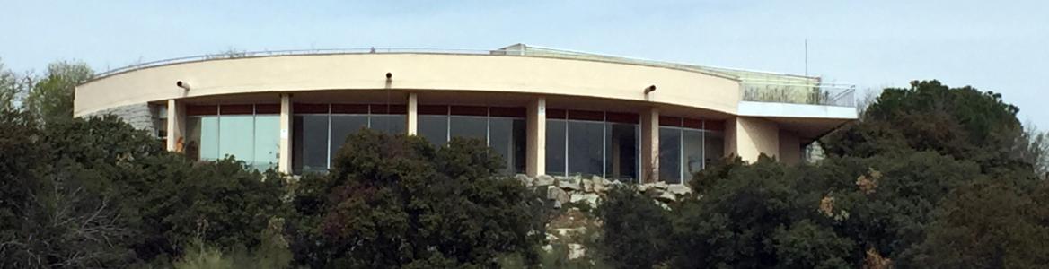 Fachada circular del edificio con cristalera y muro exterior con vegetación