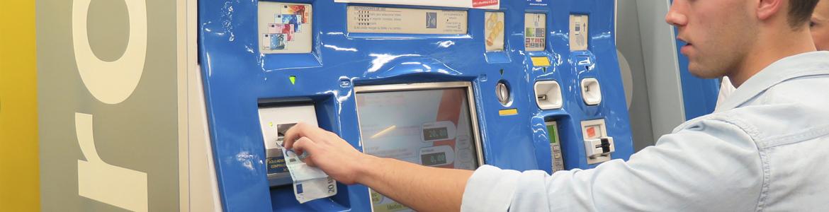 Imagen de hombre joven introduciendo un billete en una máquina expendedora de Metro