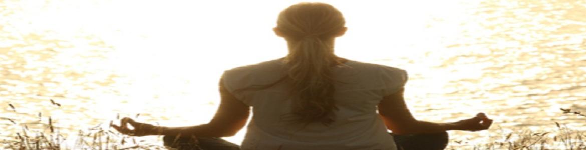 Mujer meditando sentada mirando al sol