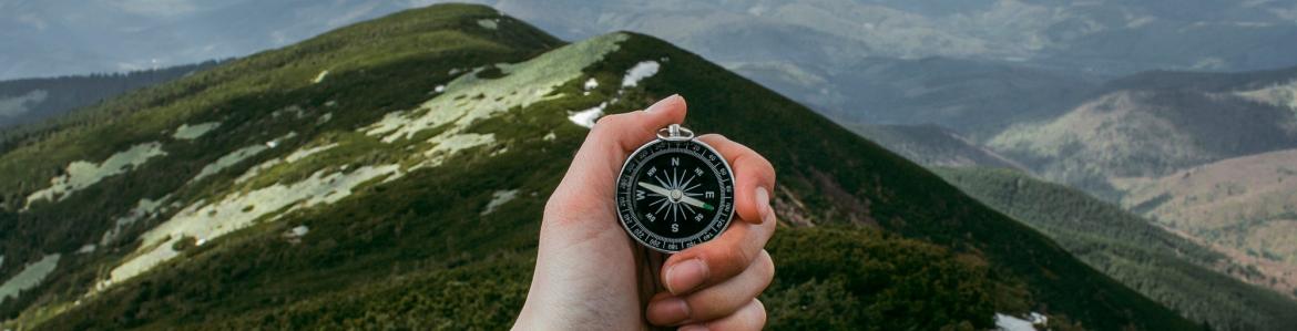 mano sosteniendo una brújula con paisaje de montaña al fondo