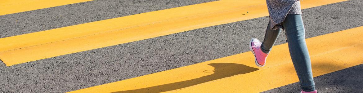 Young man crossing yellow striped zebra crossing