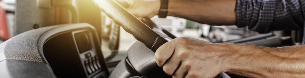 Man hands on steering wheel driving industrial vehicle